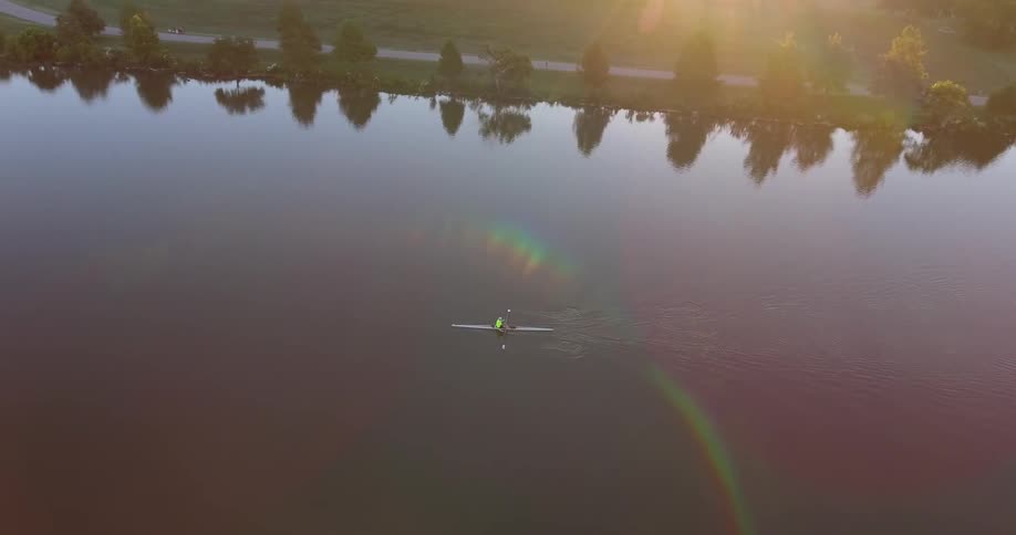 A person in a kayak on a smooth river in the morning