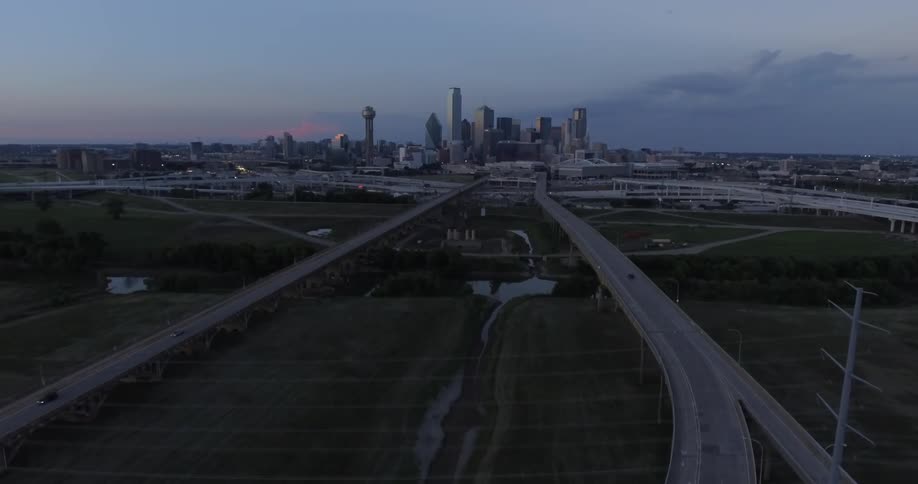 A few cars travel on a freeway that goes toward a city in the distance