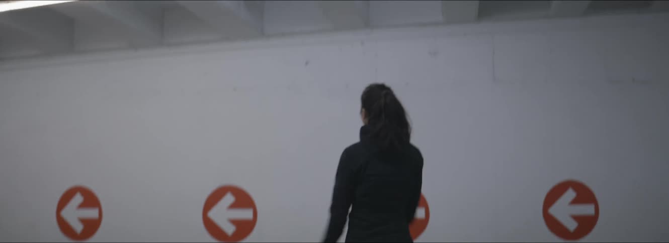 A woman in a room stretching with a wall in the background