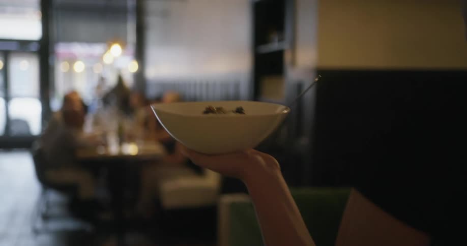 A waitress carries a dish of food to a table full of people drinking wine