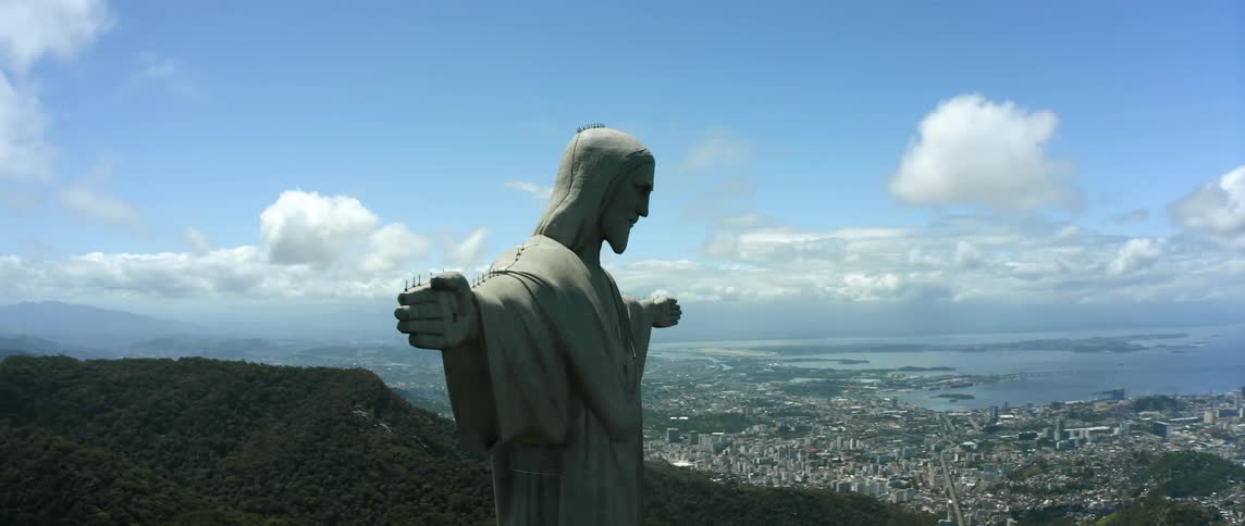 Christ the redeemer statue in rio with arms outstretched overlooking the city and coast