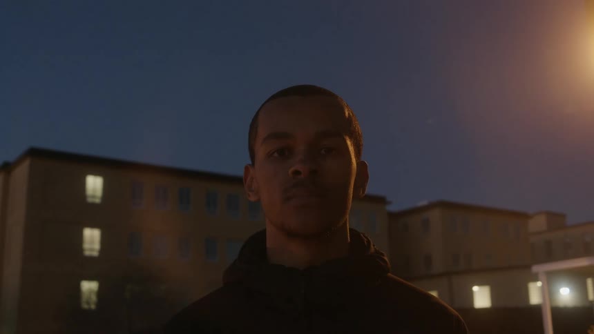 A man is standing outside of a building at sunset
