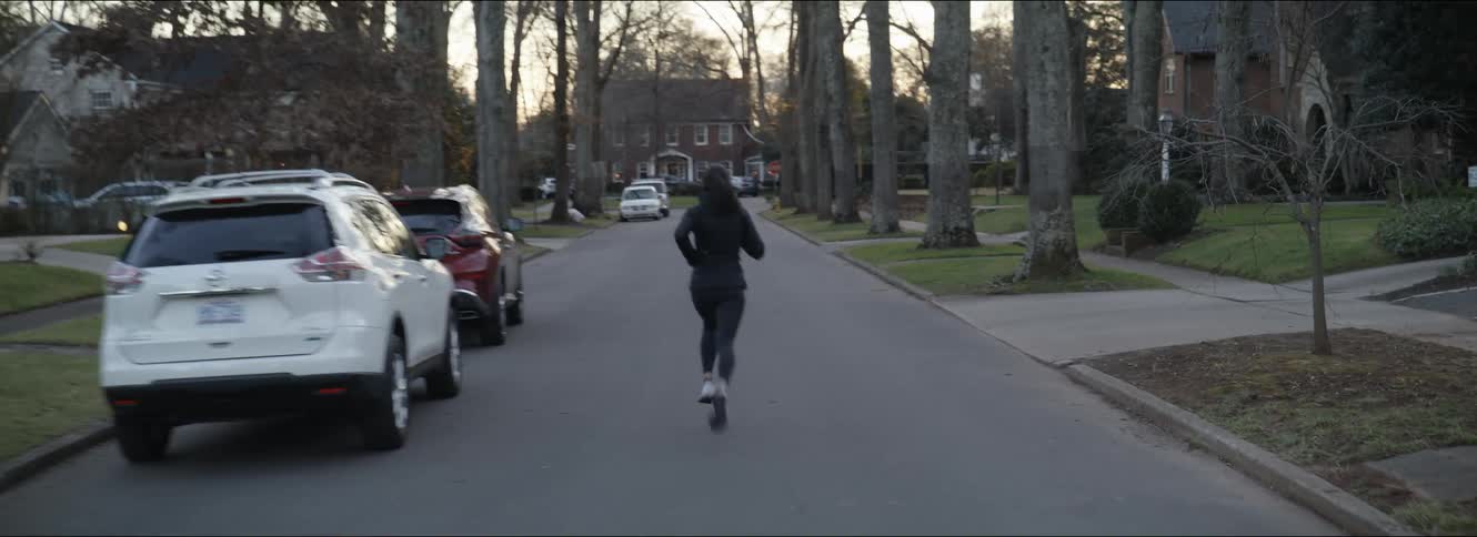 A woman jogging alone on a residential street at sunrise