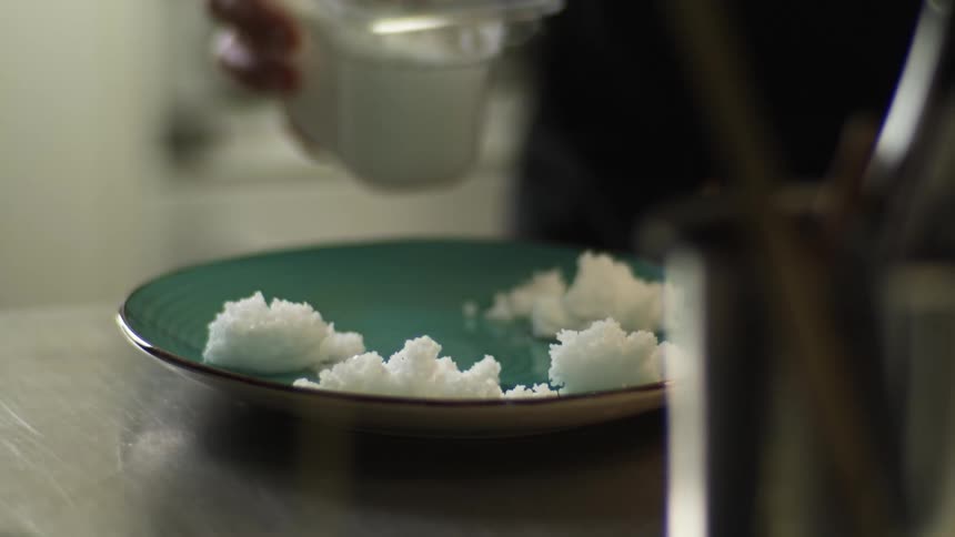 Chef serving rice with a spoon on a green ceramic plate on the restaurant kitchen