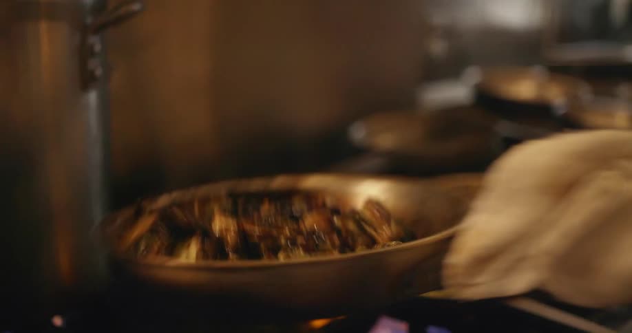 Chef tossing food on a pan over the kitchen range on a restaurant