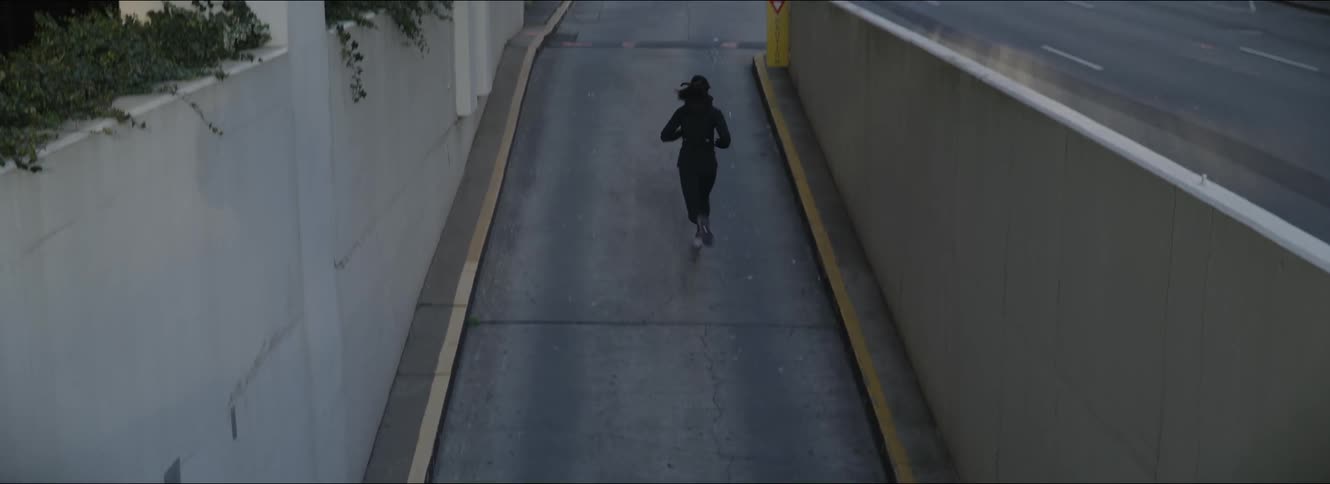 A woman runs down an alley past an apartment building downtown