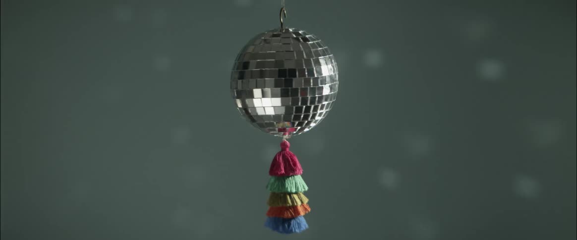 A small mirror ball is spinning and reflecting light as is casts moving light patterns on the wall of a room