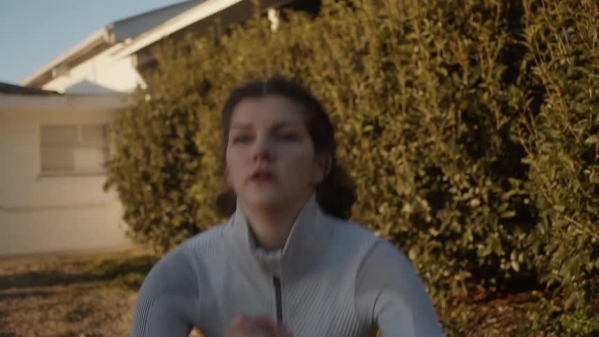 A woman is exercising outside a home in the yard