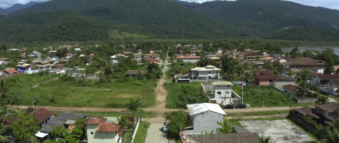 A town with houses and buildings surrounded by lush green mountains grass and dirt roads