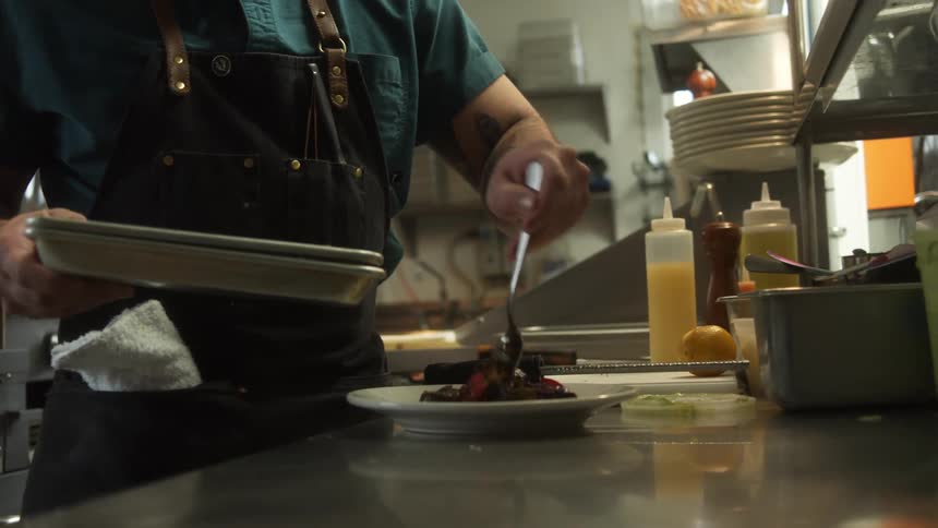 A cook plates food in an industrial kitchen