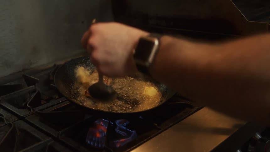 A person cooking a steak in a pan