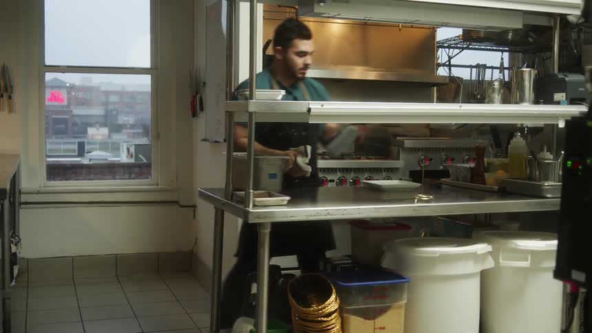 Man working in restaurant kitchen near window with view of town starts restaurant prep