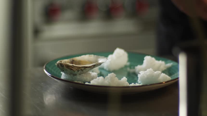 A person placing clamshells on rice on a plate on a table