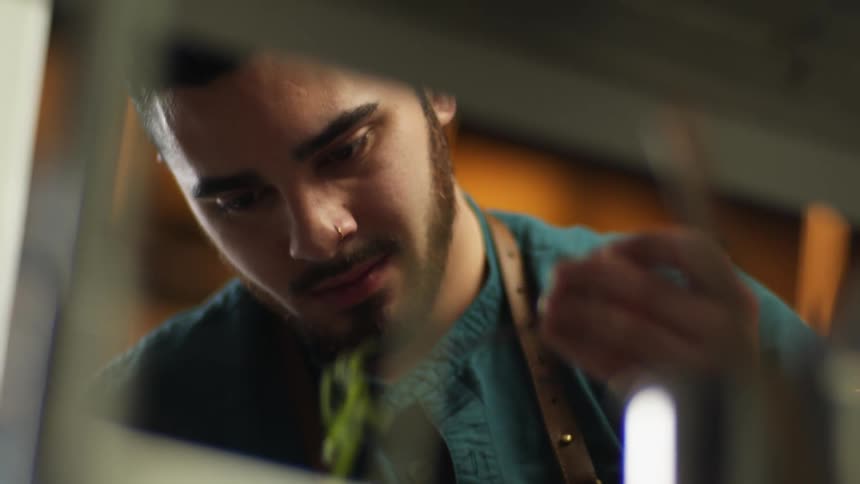 A man in a room using chopsticks to pick up vegetables