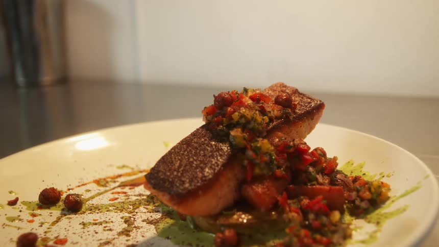 A plated meal of salmon with salsa and sauces