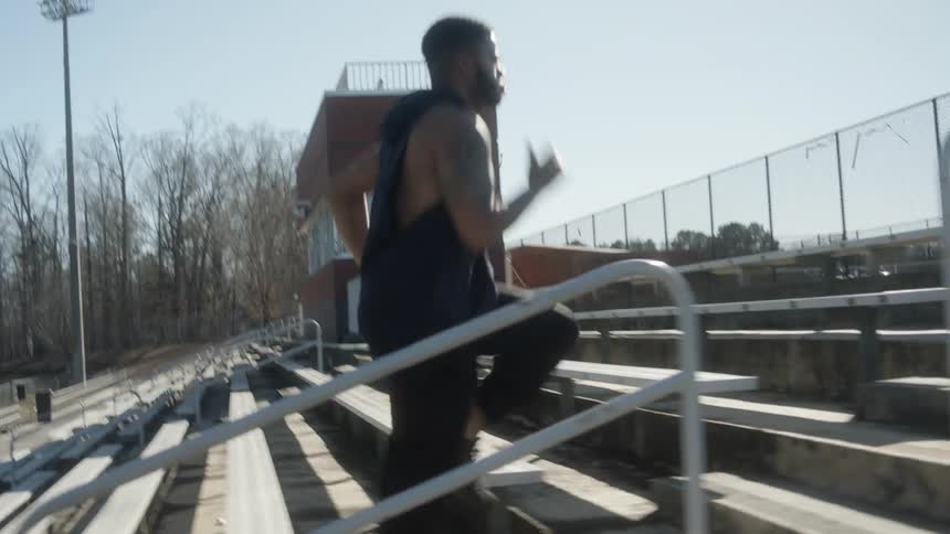 A man running up bleachers with trees the sky and clouds in the background