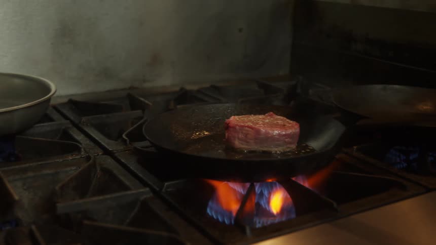 A man cooking a steak in a pan
