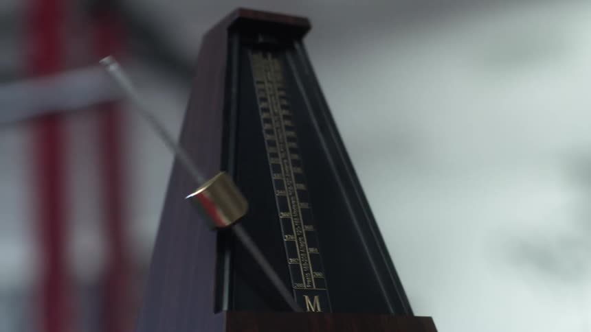 A metronome is moving as it sits in a room
