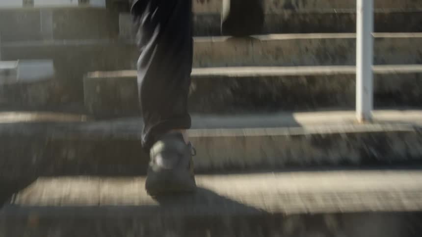 A person wearing shoes runs up a flight of stairs outdoors