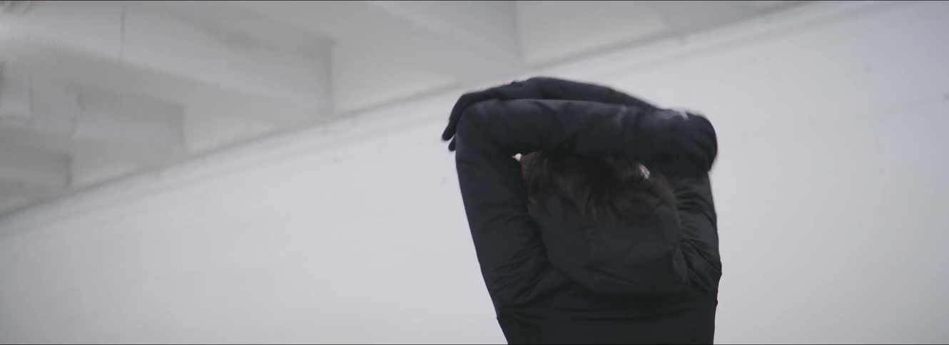 Woman with ponytail black coat and gloves warms up of jogging in car park