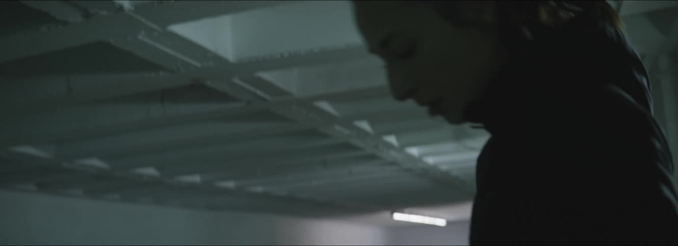A woman in a room stretching with a wall and light fixtures in the background