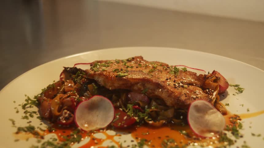 A plated entre sits on a stainless steel counter