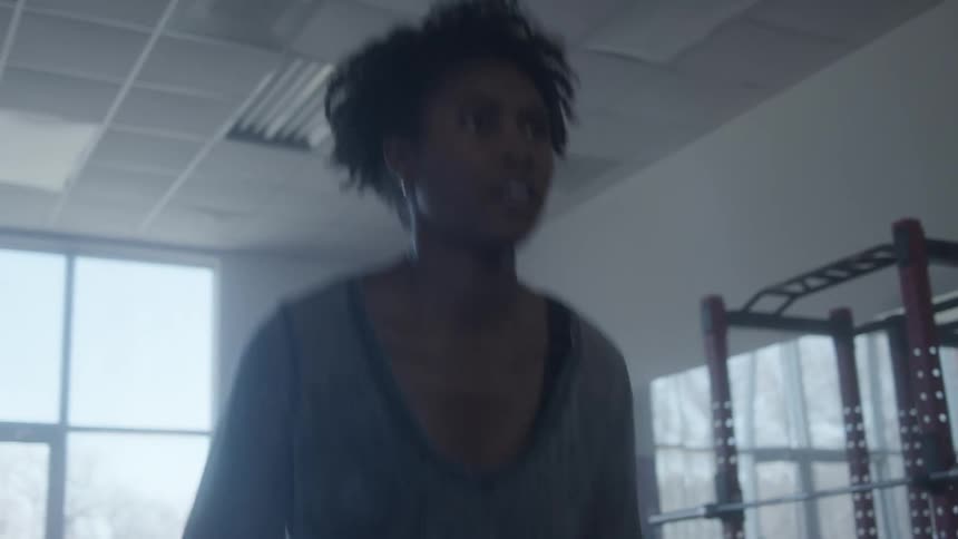 Young woman lifting weights inside a dimly lit gym