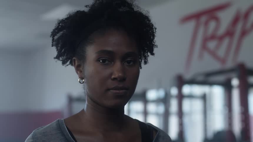 Young woman walking on a gym stops to look at the camera