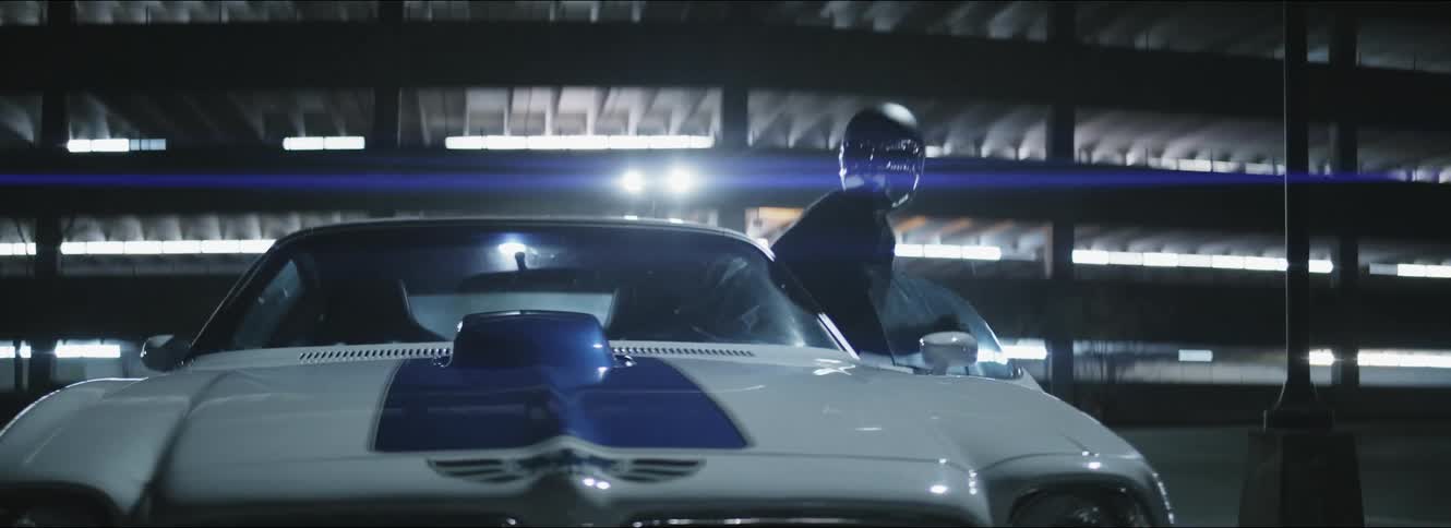 Driver wearing helmet gets into blue and white sports car parked in parking garage