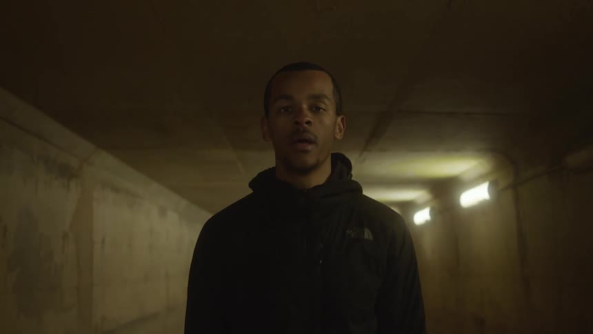 A man stands up and catches his breath in a dimly lit corridor