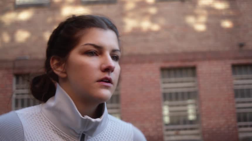 Young strong woman works out on the backyard of a building