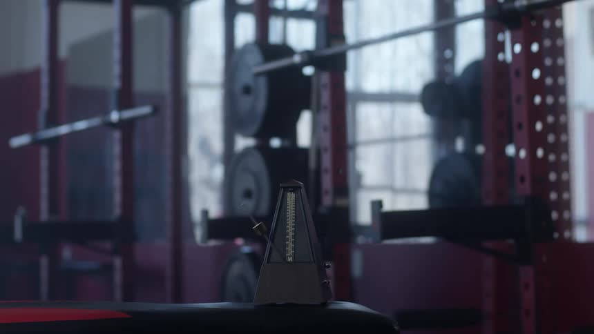 A metronome is set a top a bench near weight racks