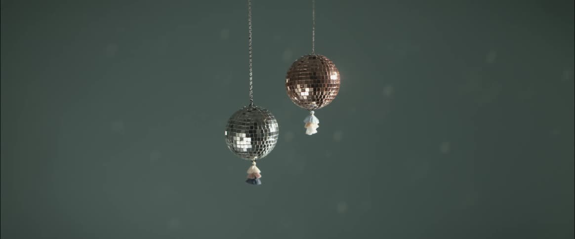 A close up of two small disco balls hanging by threads