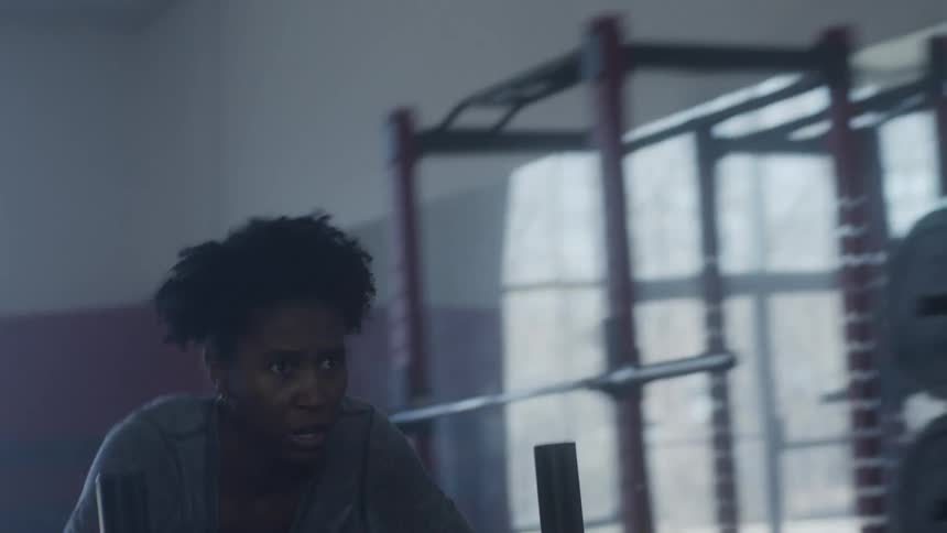 Woman with curly hair pushes weight in the gym