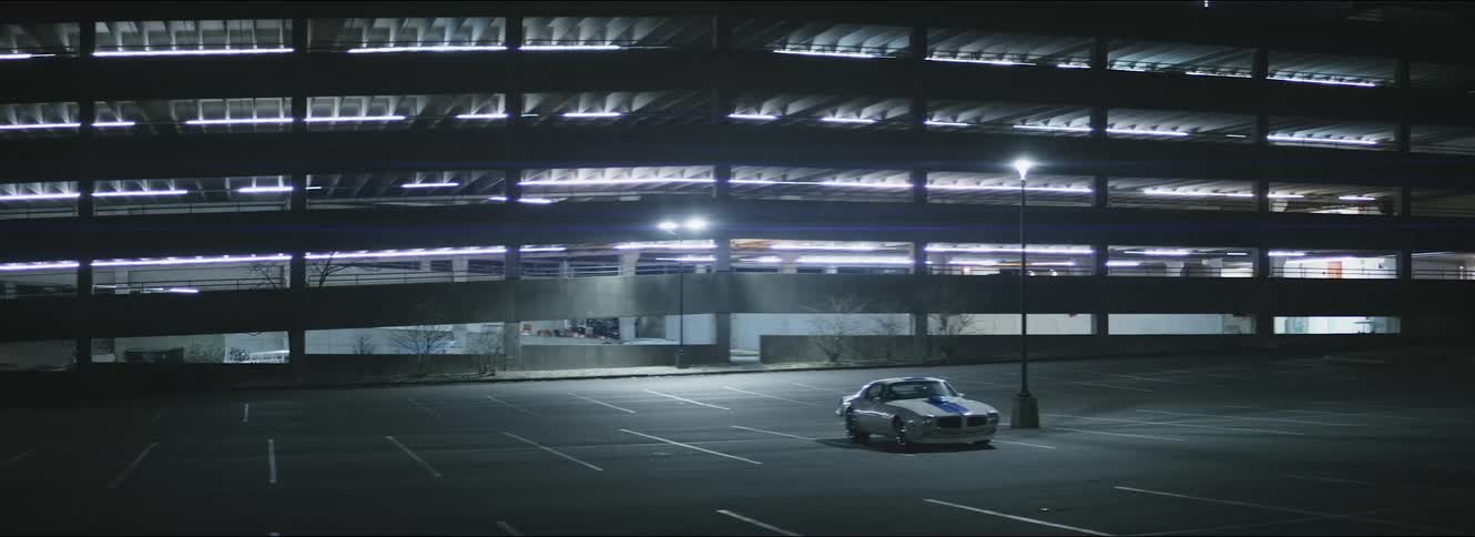 A lone car is parked in the lot at night