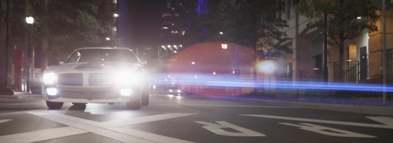 A white sportscar is driving down a city street