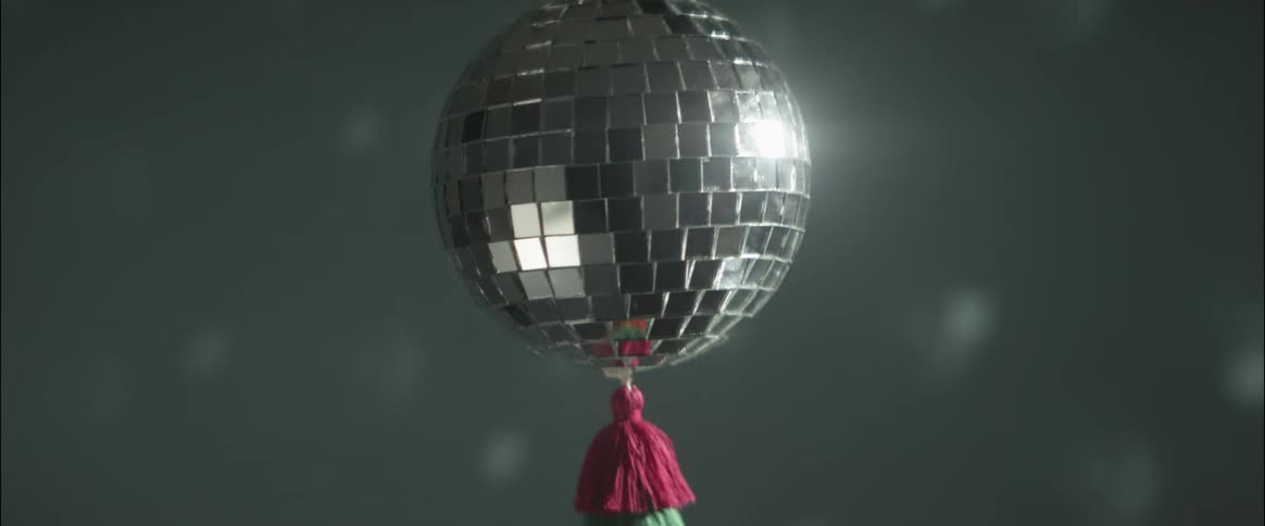 Small spinning disco ball hanging from the ceiling reflecting light on the walls