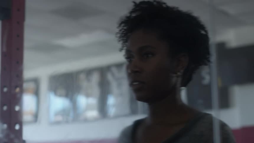 A woman leans on a gym mirror with her hand looks at her reflection then walks away