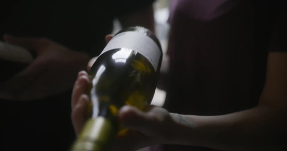 Woman and man with black t shirt hold and look over wine bottle