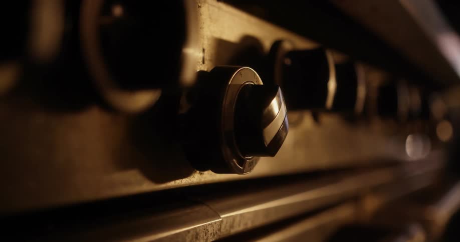 A hand turns a dial on a stove