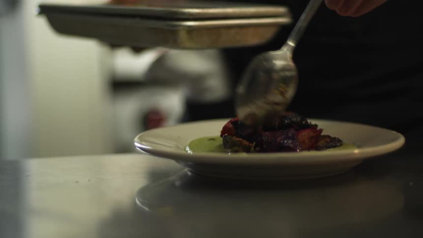 Chef serving food on a dish on the restaurant kitchen counter top
