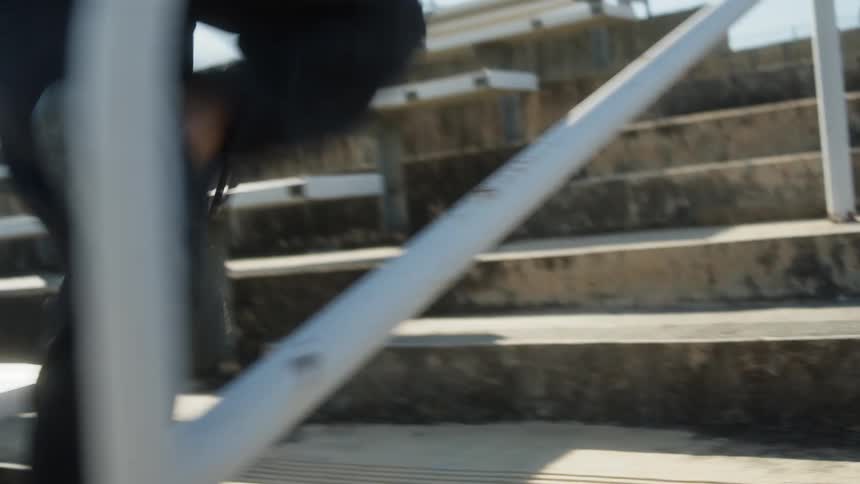 Man runs up concrete steps toward fenced barrier at top of stadium
