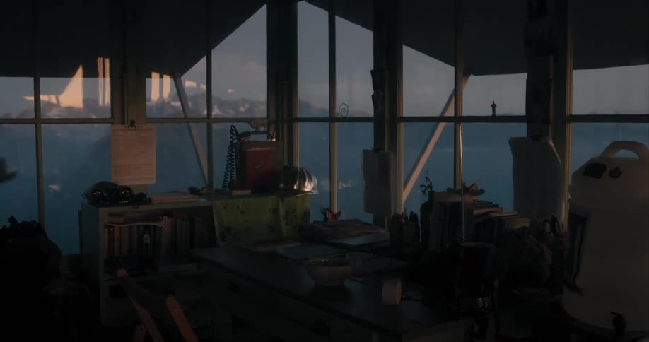 An empty watchtower office overlooking a large body of water with mountains at dusk