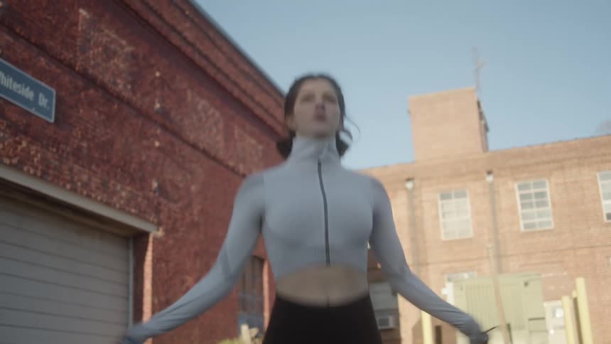 A woman jumping rope while exercising outside near brick buildings