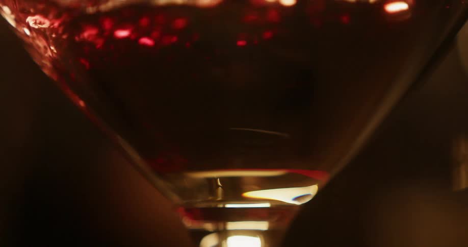 Red wine fills wine glass creating little bubbles