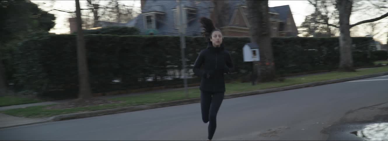 A woman is jogging through the neighborhood