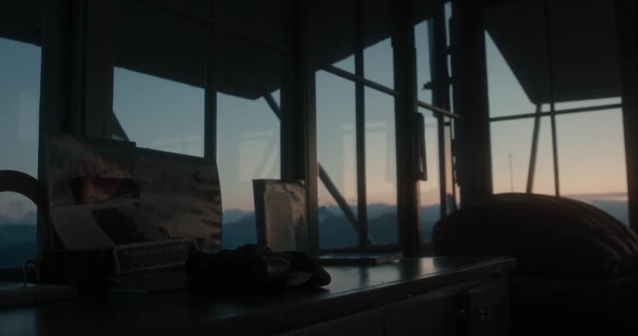 A map and a sign sit on a desk in an observatory with views of nearby mountains
