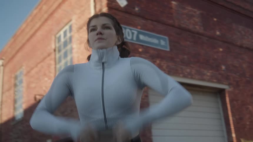 Woman with grey sport shirt and black leggings works out in the street