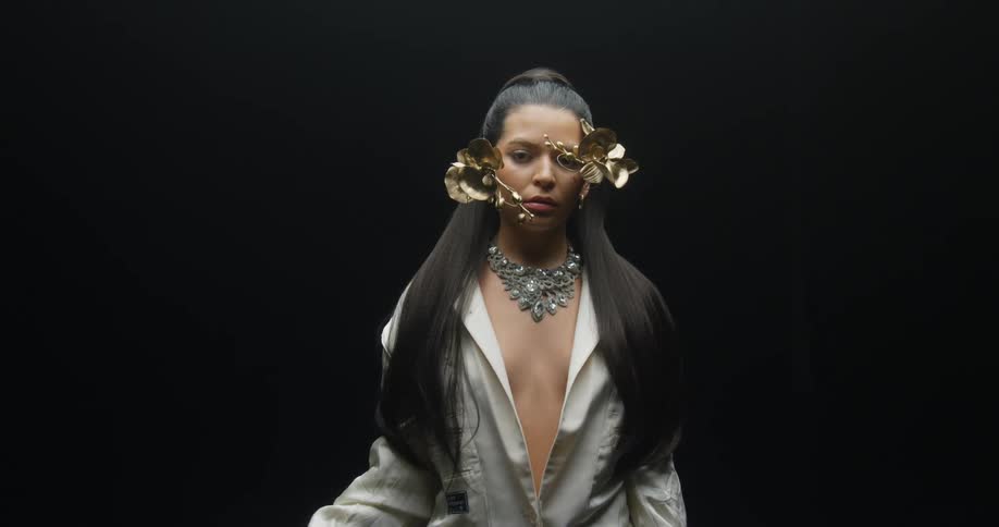 A female model poses with some floral accessories placed around her face