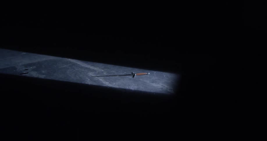 A sword sits on the ground in the dark room